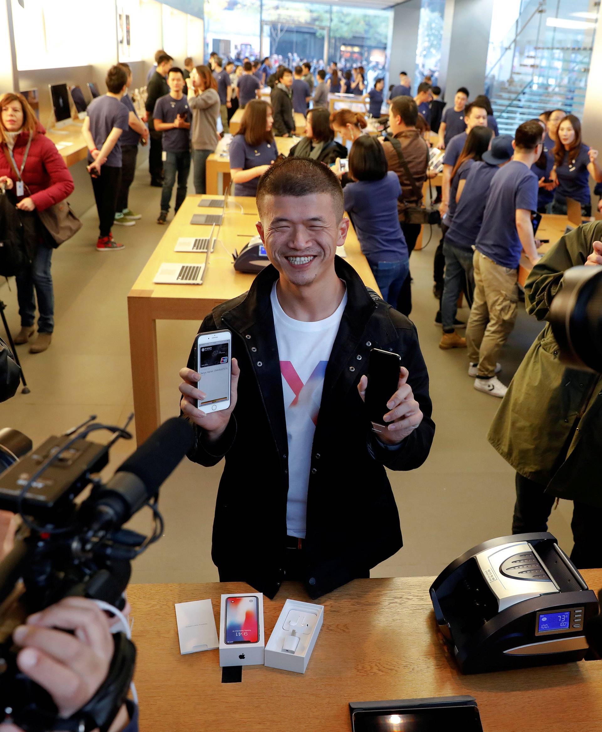 The first customer shows his new iPhone X after buying it at an Apple Store in Beijing