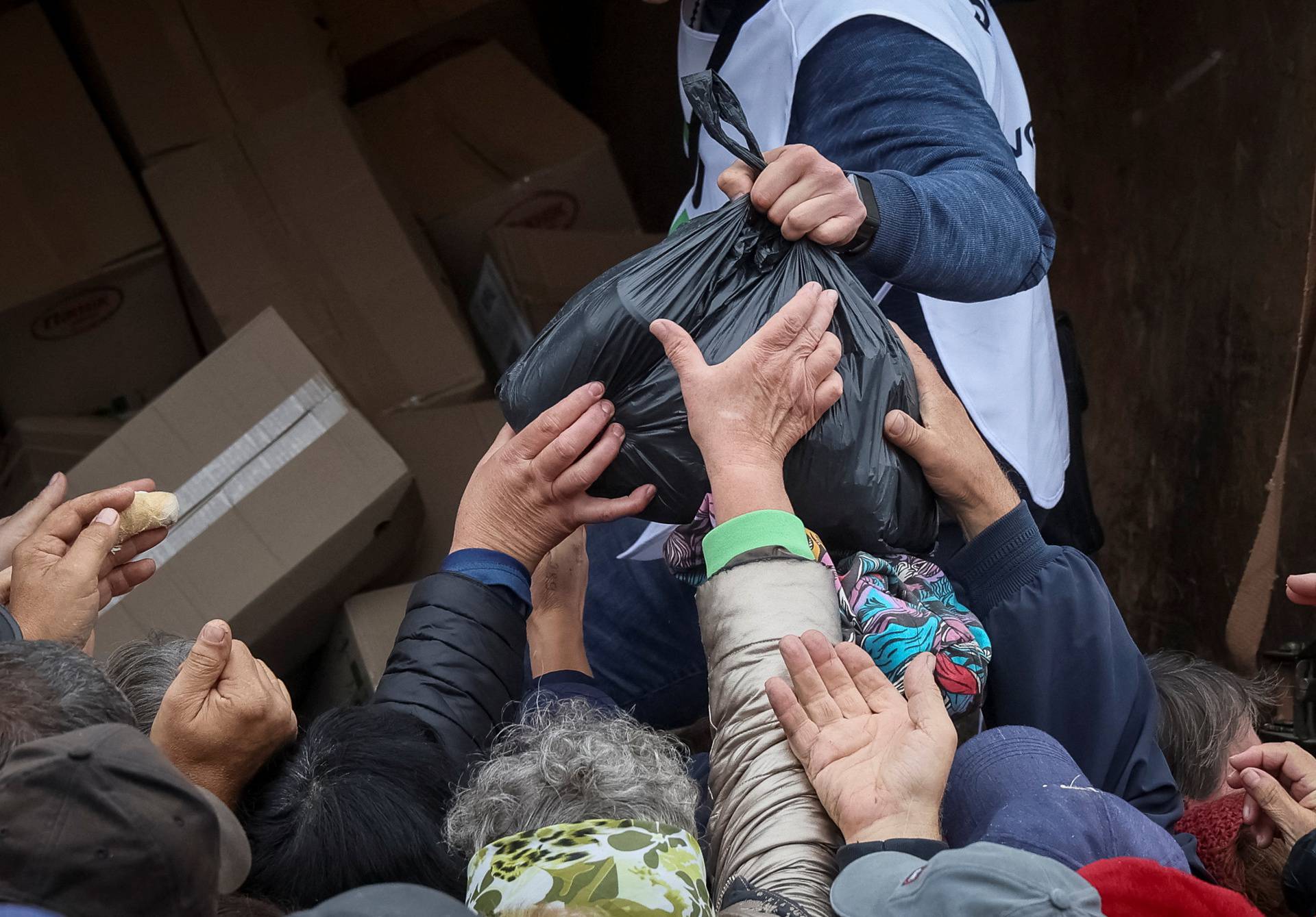 Local residents crowd near a car distributing humanitarian aid in the town of Balakliia