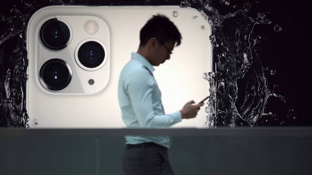 FILE PHOTO: A man walks next to an advertisement for Apple's new iPhone 11 Pro at the Apple Store in IFC, Central district, Hong Kong, China