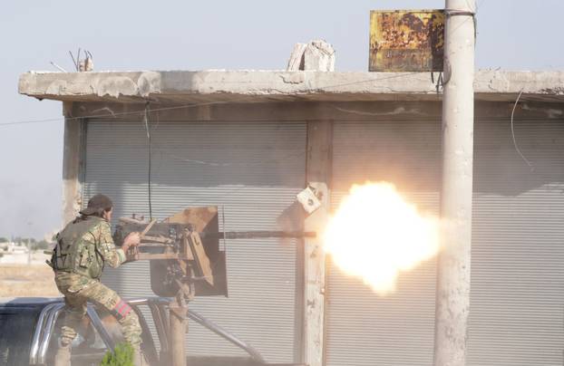A Turkey-backed Syrian rebel fighter fires a weapon in the town of Tal Abyad