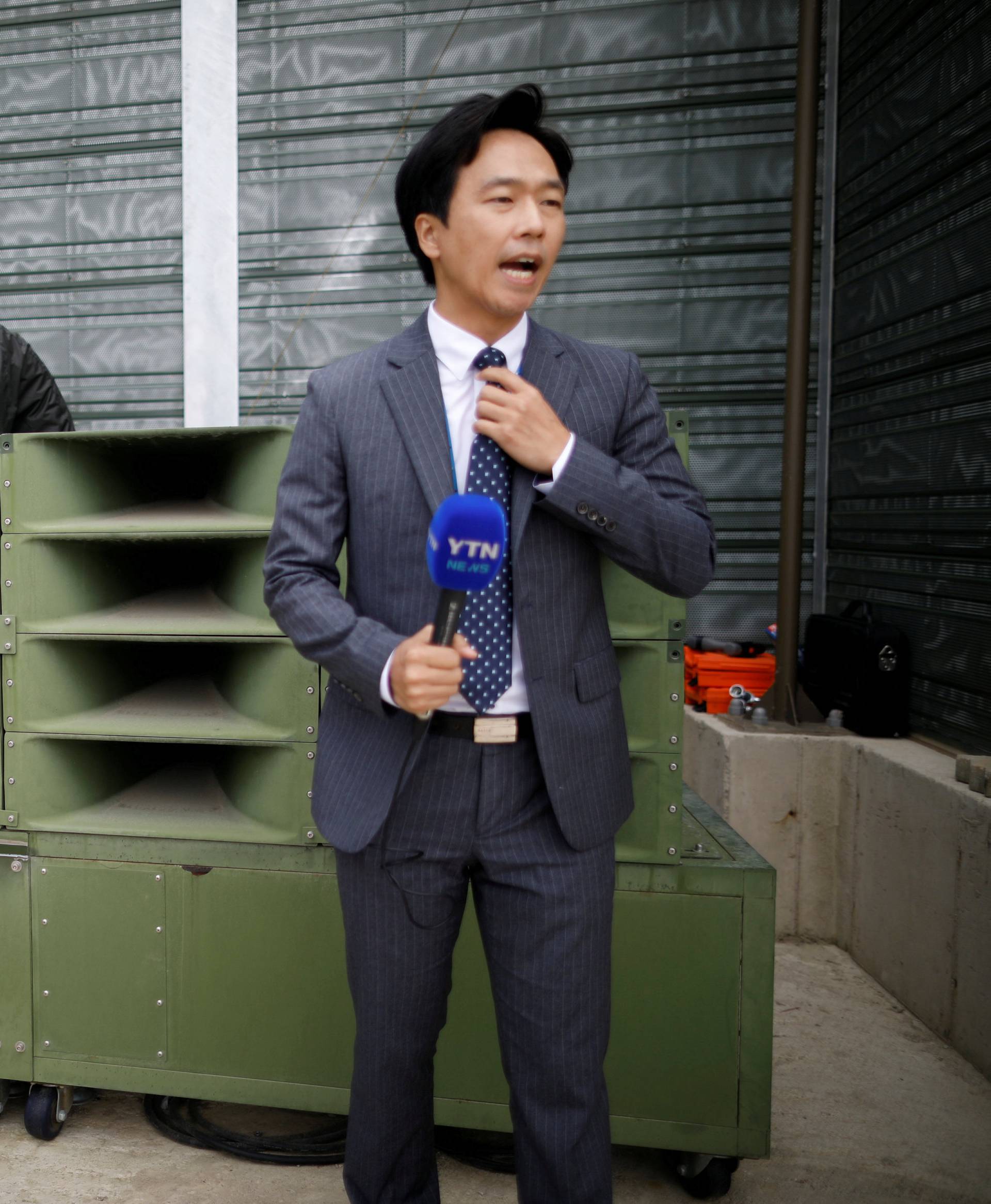 A reporter prepares a news report as South Korean soldiers dismantle loudspeakers that were set up for propaganda broadcasts near the demilitarized zone separating the two Koreas in Paju