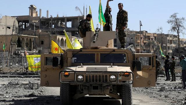 A Fighter of Syrian Democratic Forces takes a selfie as he stands on a military vehicle in Raqqa