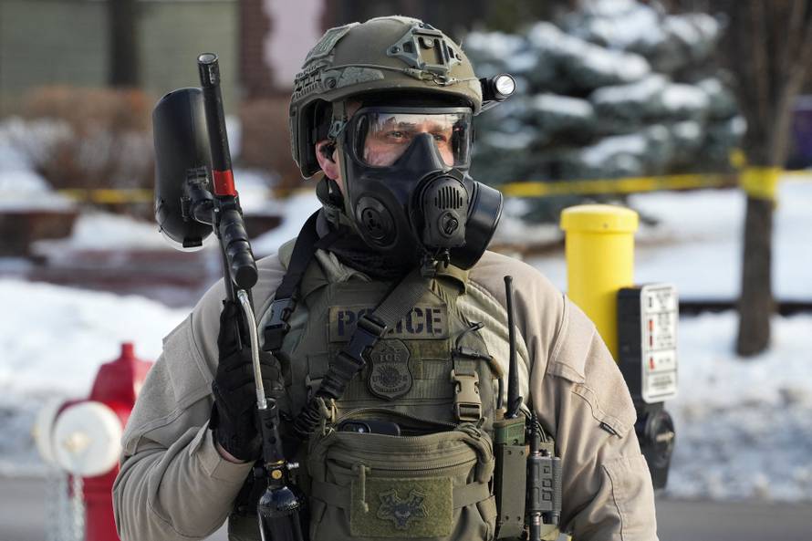 A member of U.S. Immigration and Customs Enforcement (ICE) stands guard at the scene where a driver was shot by a U.S. immigration agent, according to local and federal officials, in Minneapolis