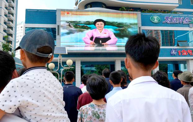 North Koreans watch a news report showing North Korea