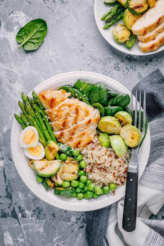 Healthy grilled vegetables buddha bowl with chicken and quinoa, spinach, egg, zucchini, asparagus, Brussels sprouts and green peas