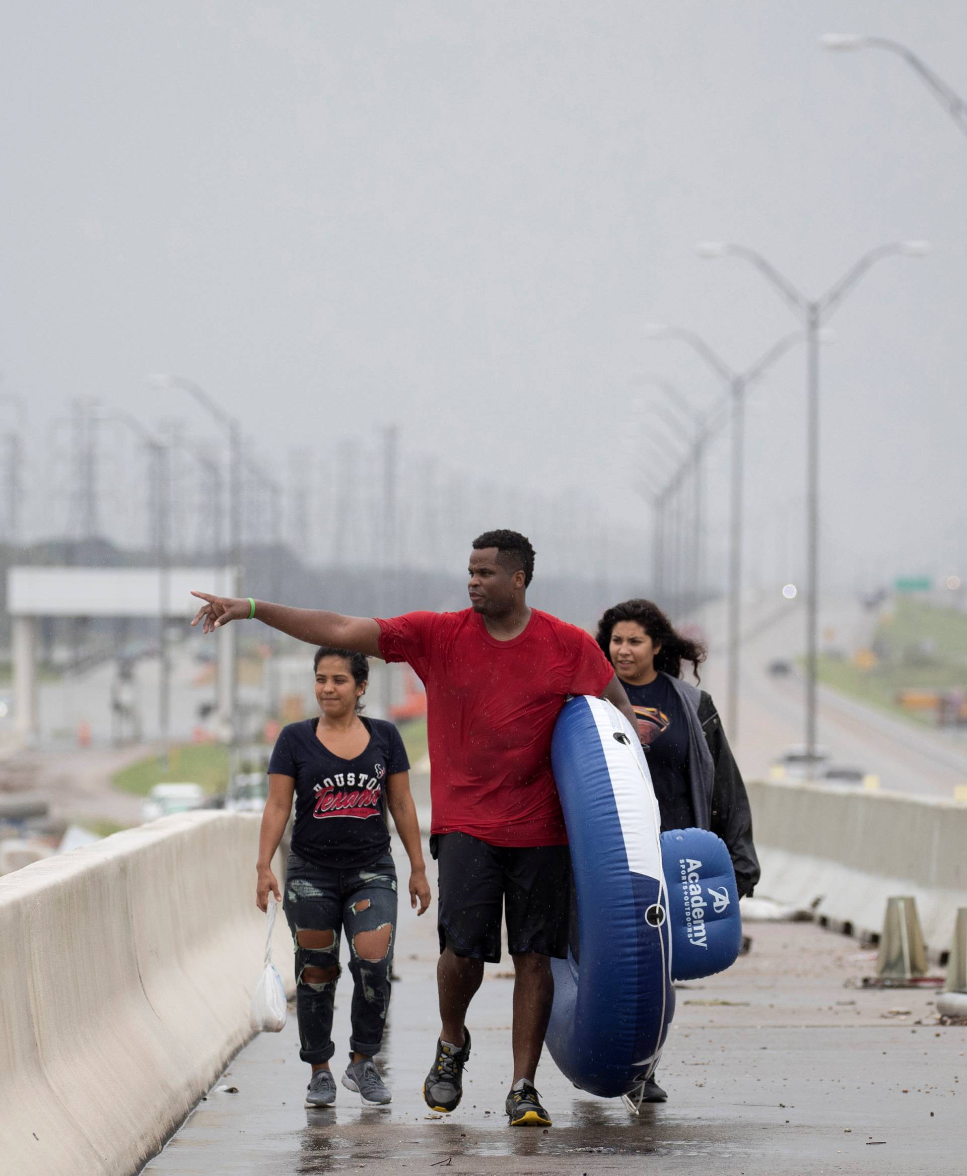 Jeremy Collier points toward a flooded shopping center after rescuing his wife Anna Collier and friend Melissa Merito from flood waters in Pearland, in the outskirts of Houston