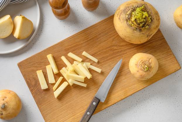Cutting fresh yellow turnip for cooking healthy vegan food