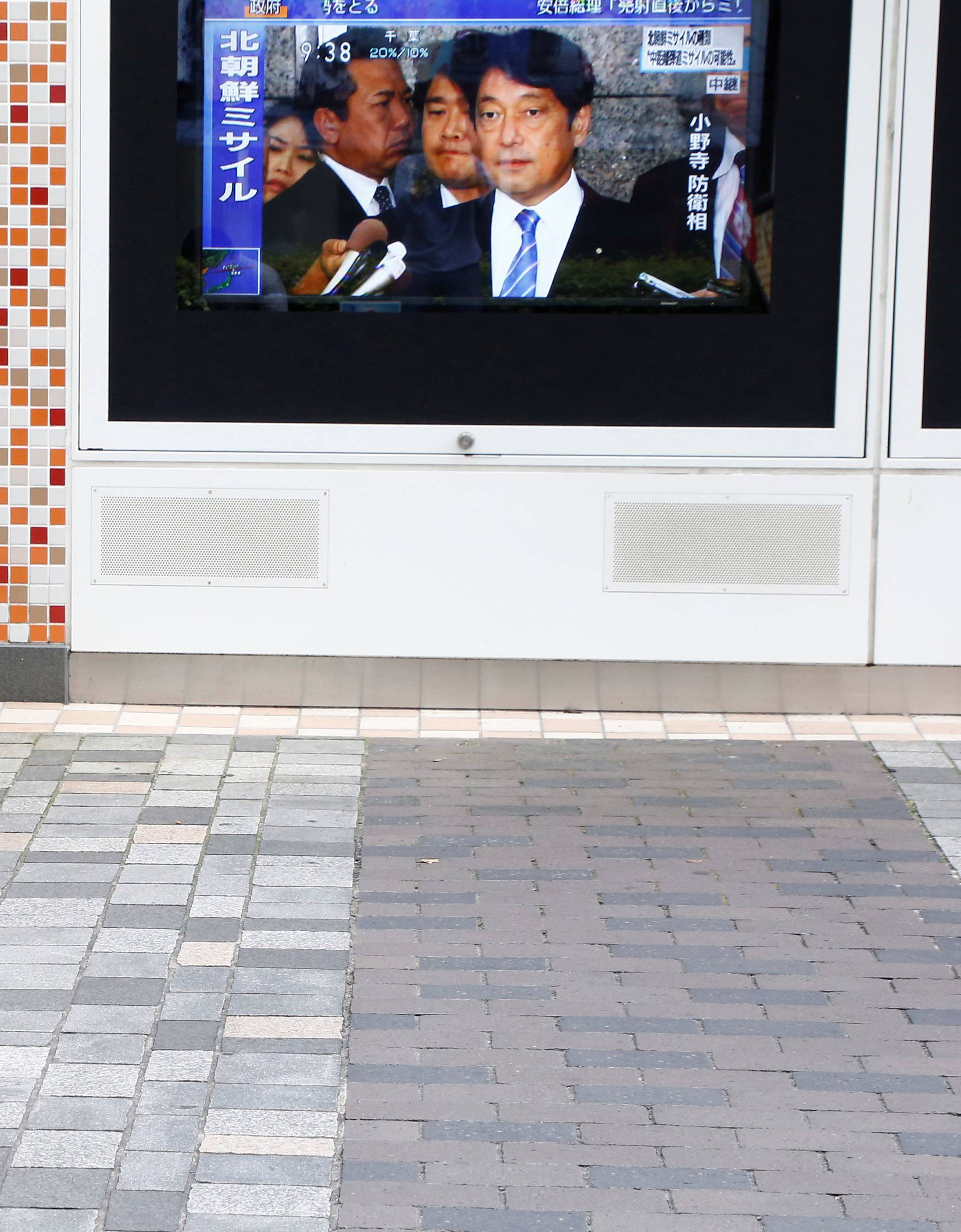 Pedestrian walks past a TV set showing news about North Korea's missile launch in Tokyo