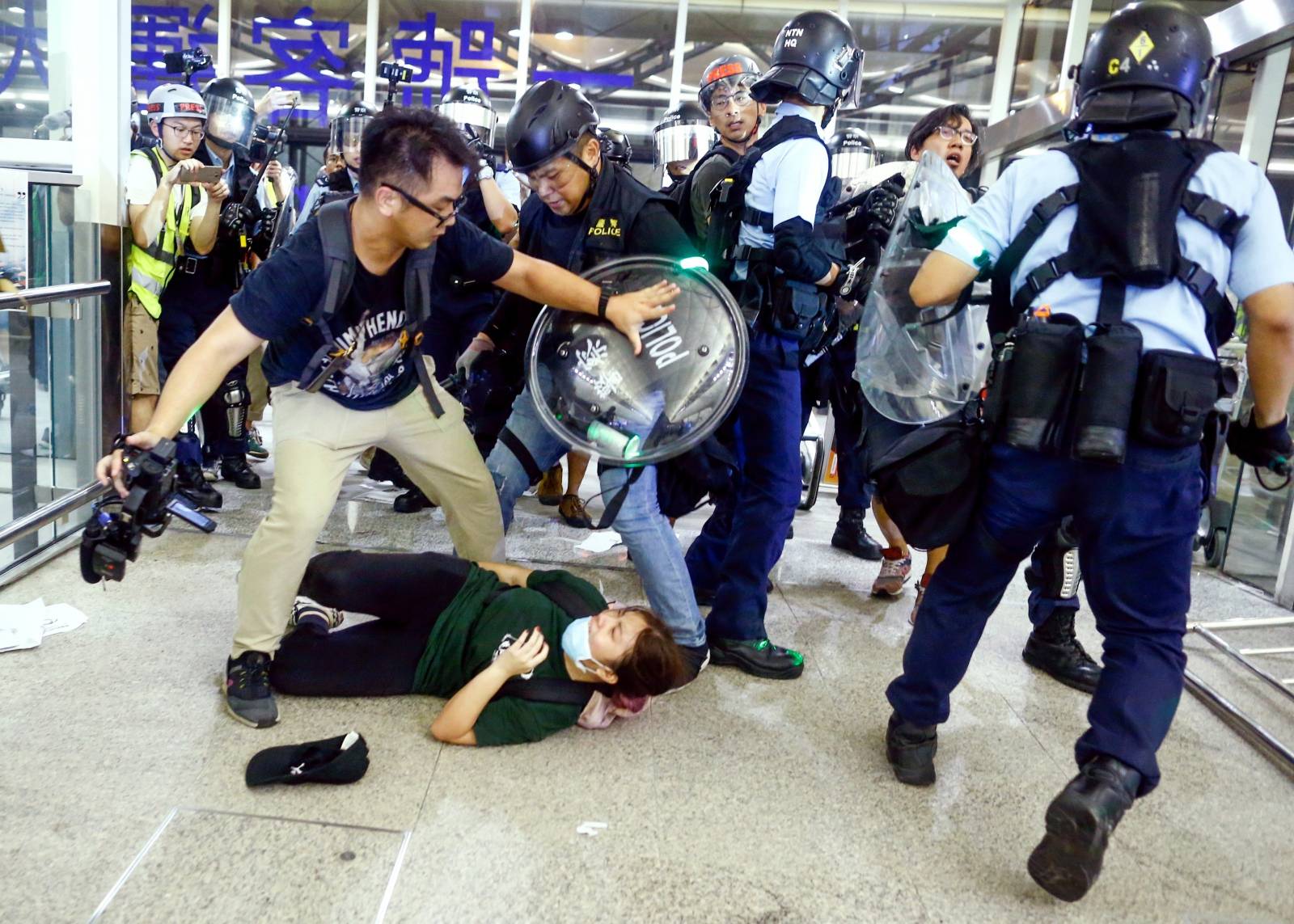 Riot police disperse anti-extradition bill protesters during a mass demonstration after a woman was shot in the eye, at the Hong Kong international airport, in Hong Kong