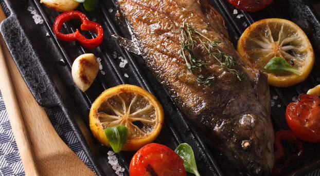 Fish menu: trout with vegetables on a grill pan close-up