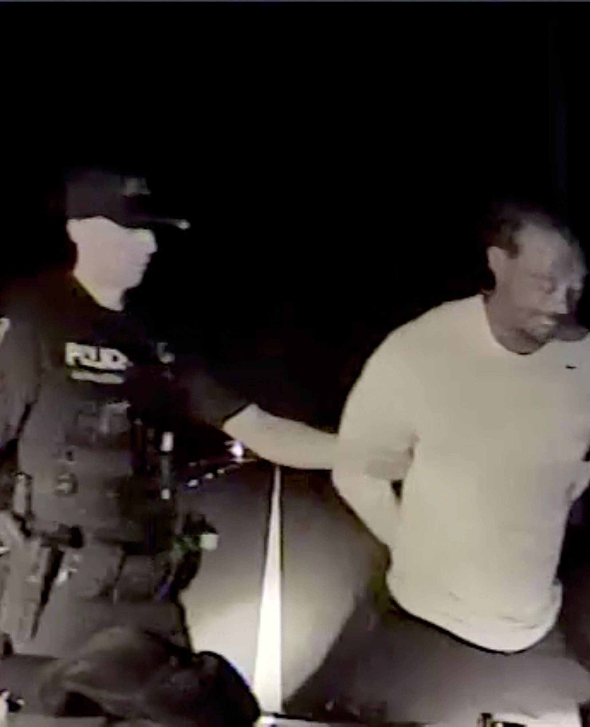 Tiger Woods is seen handcuffed and arrested by police officers in this still image from police dashcam video in Jupiter