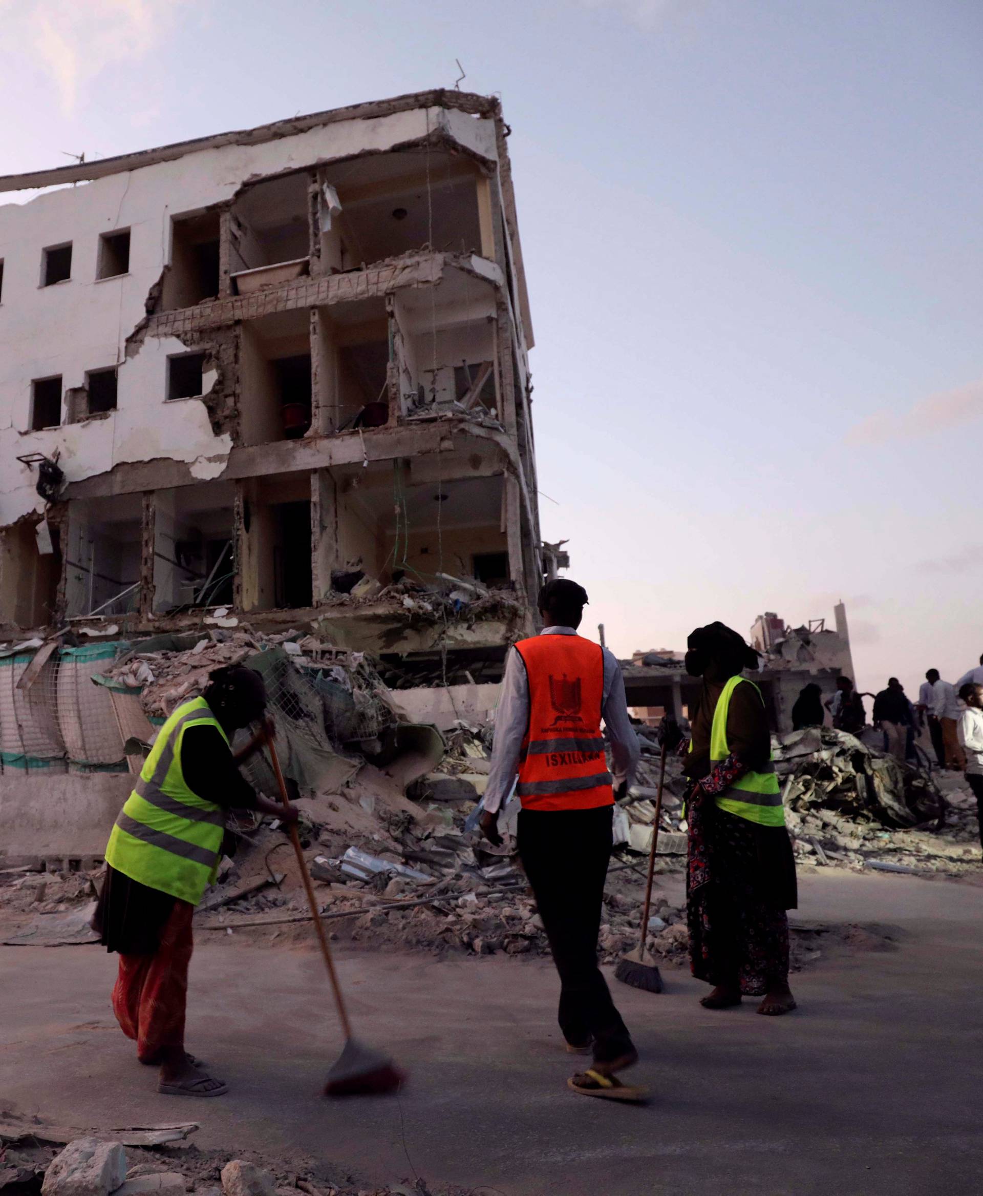 Workers clean rubble near damaged buildings after a suicide car bomb exploded, targeting a hotel in a business center in Maka Al Mukaram street, Mogadishu