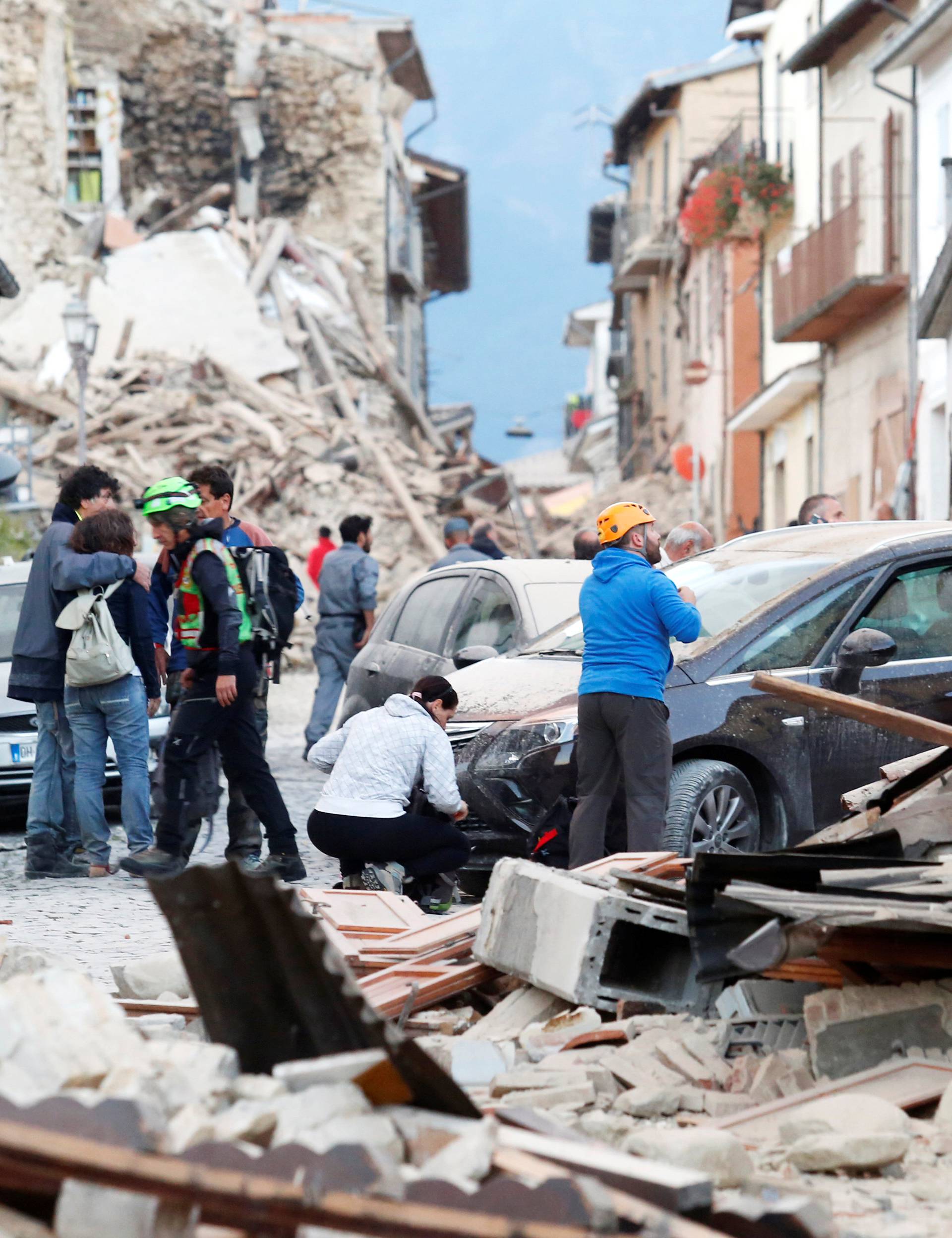 People stand along a road following a quake in Amatrice