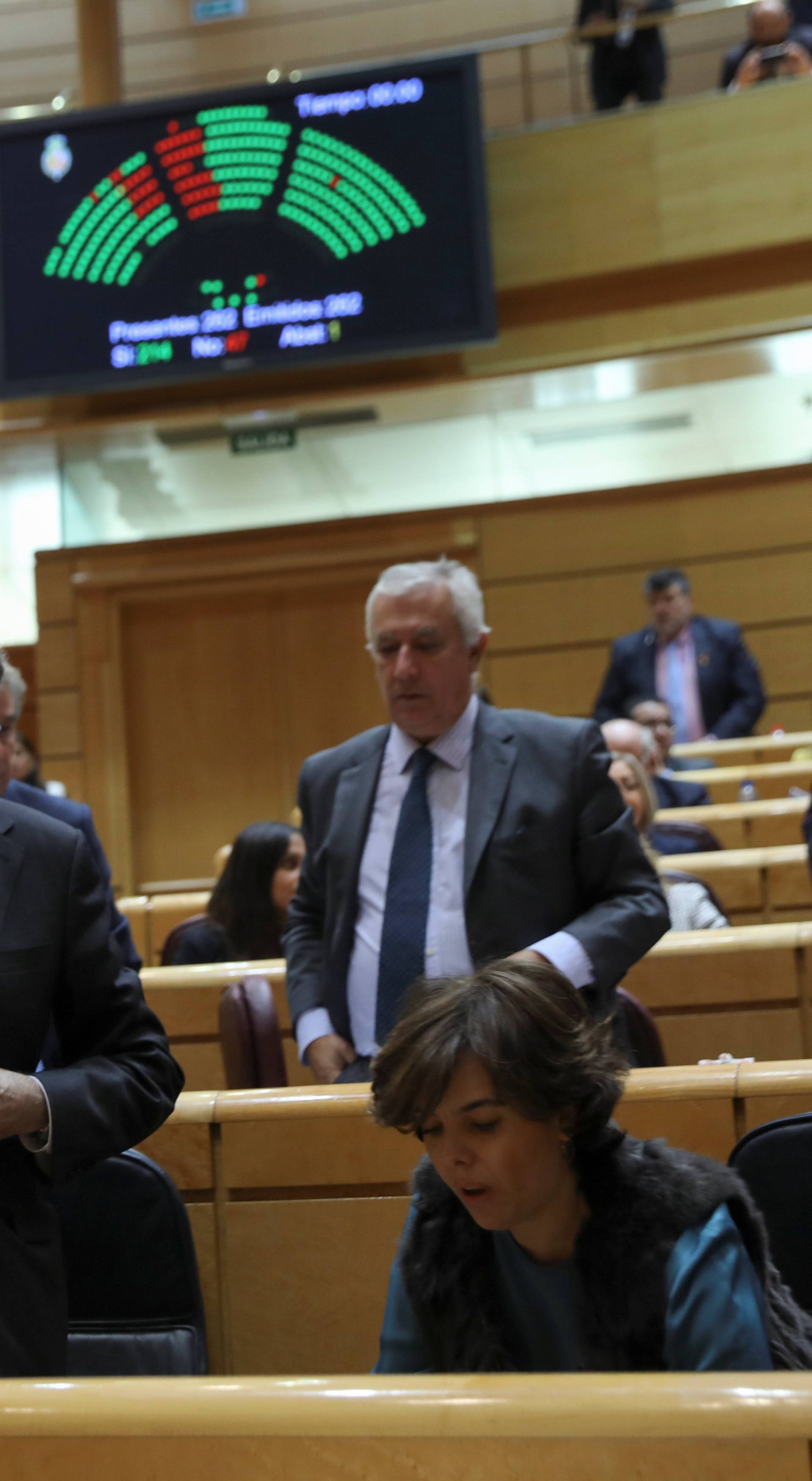 Spain's PM Rajoy and Deputy PM Saenz de Santamaria leave their seats as the results of a vote in the upper house Senate approving emergency measures to take control of the Catalan government are seen in a scoreboard in Madrid