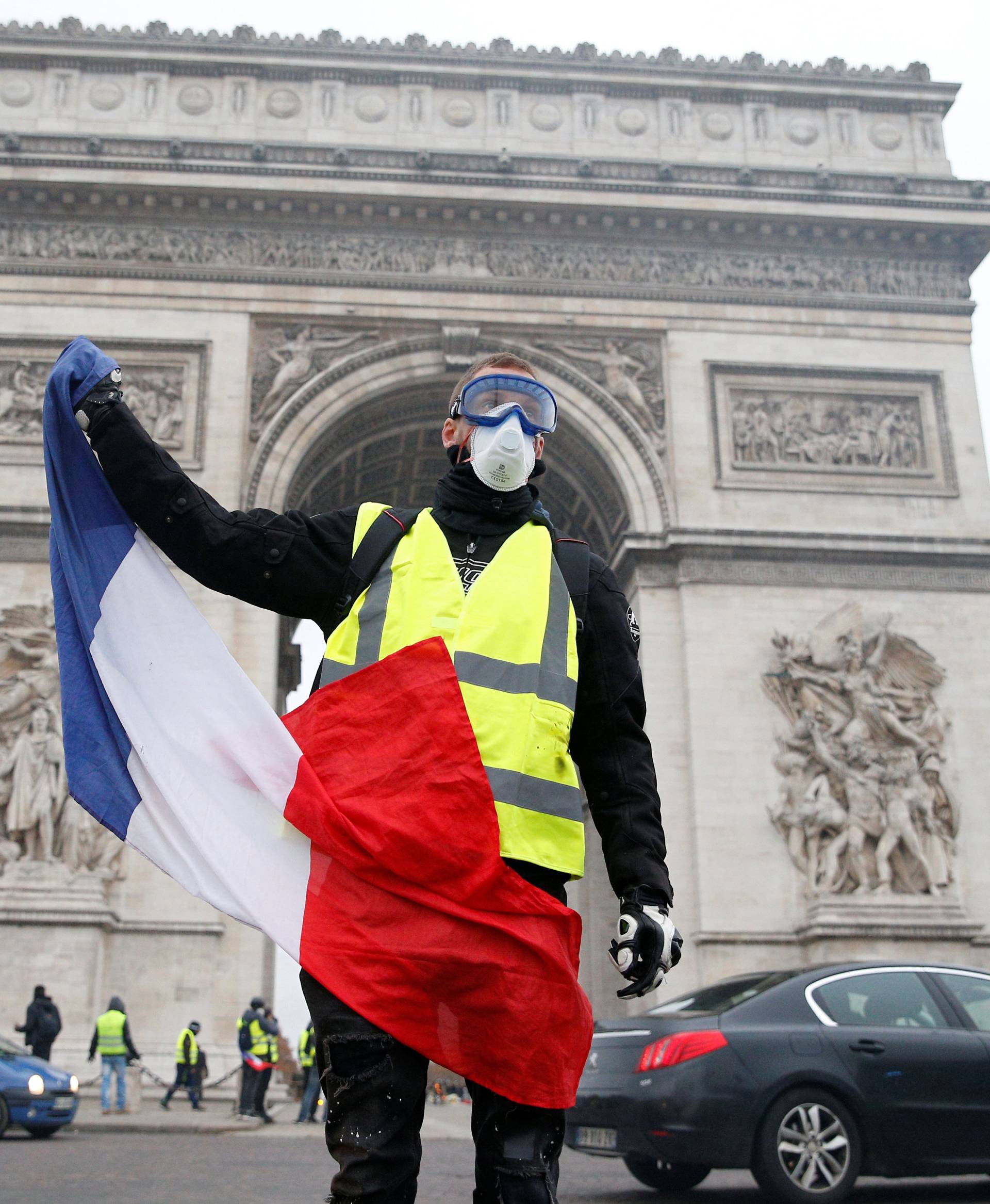 A man waves a French flag near the Arc de Triomphe as protesters wearing yellow vests, a symbol of a French drivers' protest against higher diesel taxes, demonstrate in Paris