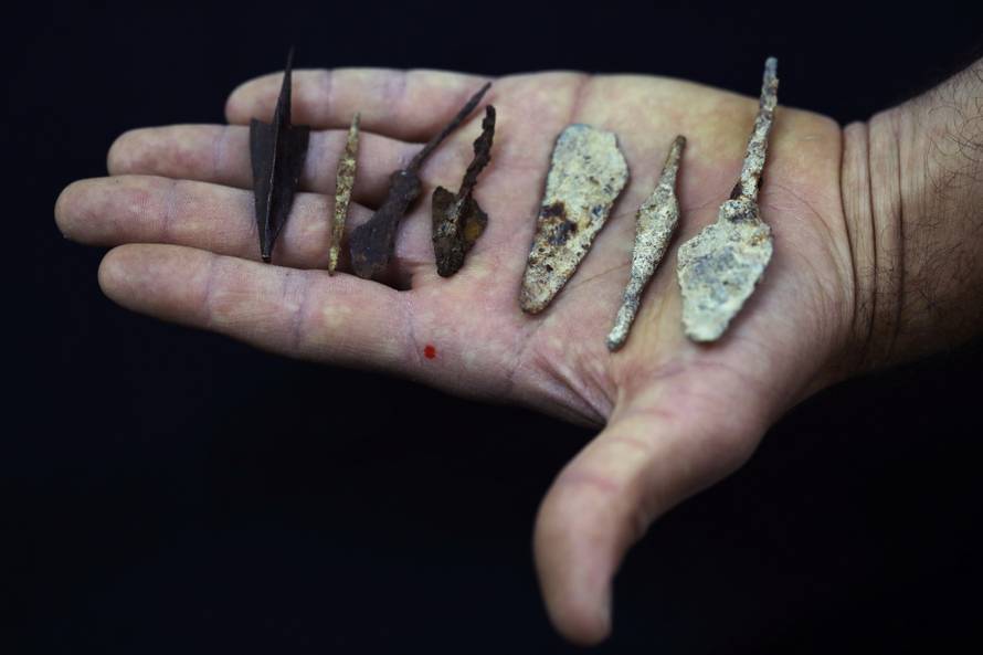 An employee holds ancient arrow and spear heads, part of various artefacts recently discovered in the Judean Desert caves along with scroll fragments of an ancient biblical texts, during an event at Israel Antiquities Authority laboratories in Jerusalem