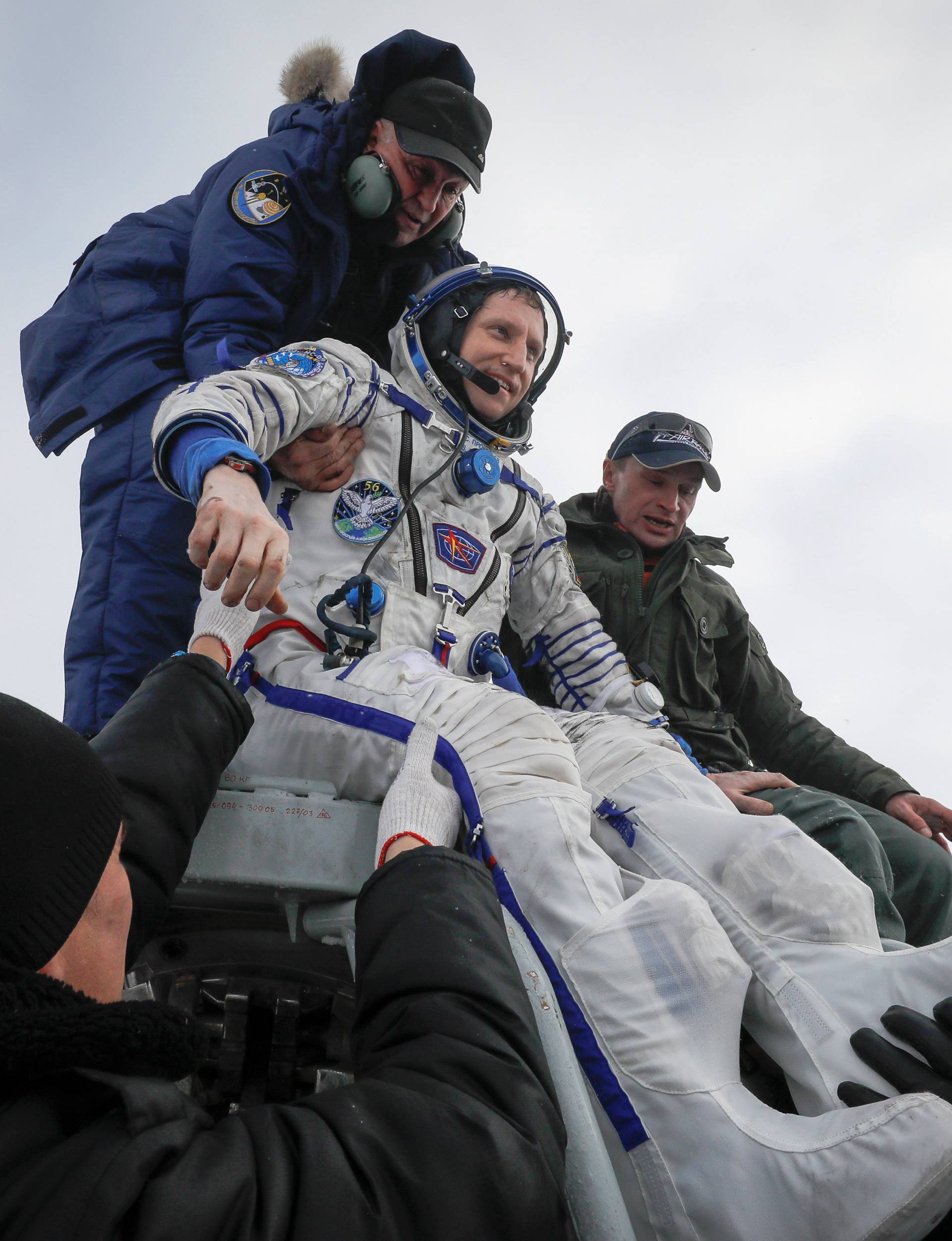 Ground personnel help International Space Station crew member Prokopyev to get out of a Soyuz capsule after landing near Zhezkazgan