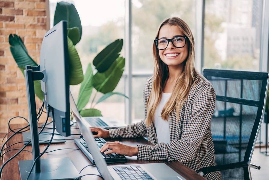 A,Smiling,Businesswoman,Types,At,A,Computer,In,A,Bright