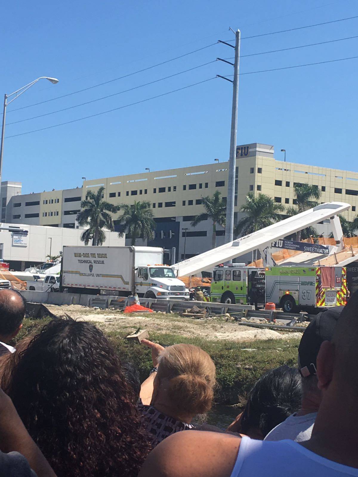People gather at the scene of a collapsed pedestrian bridge at Florida International University in Miami