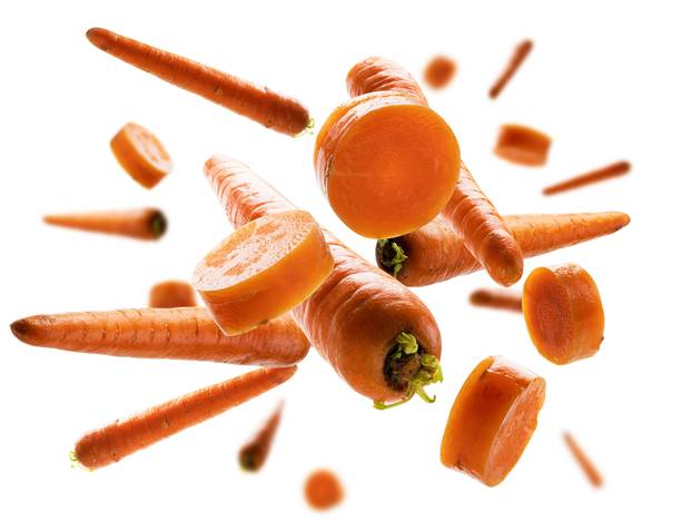 Ripe carrots whole and sliced levitate on a white background