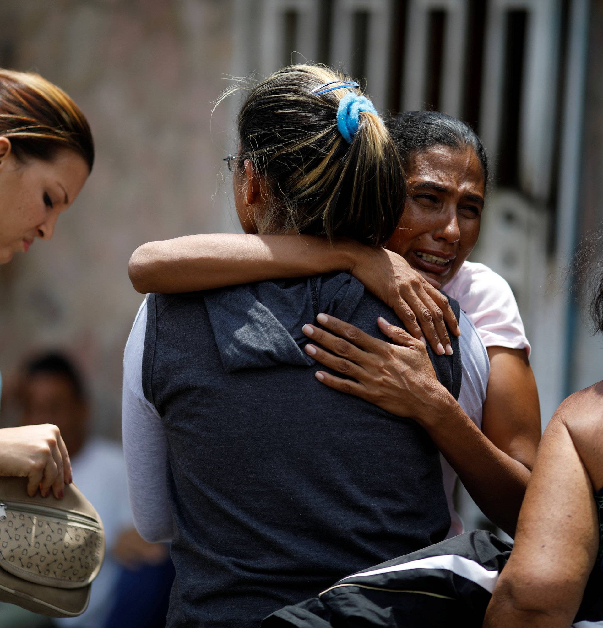 Relatives of the inmates who died during a riot and a fire in the cells of the General Command of the Carabobo Police, react outside a funeral home in Valencia