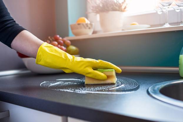 woman's hands cleaning kitchen cabinets