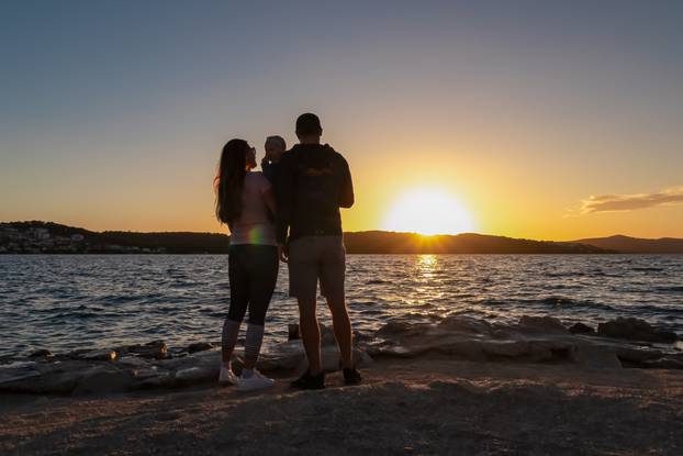 Silhouette,Of,Loving,Parents,Holding,Small,Toddler,At,Romantic,Sunset