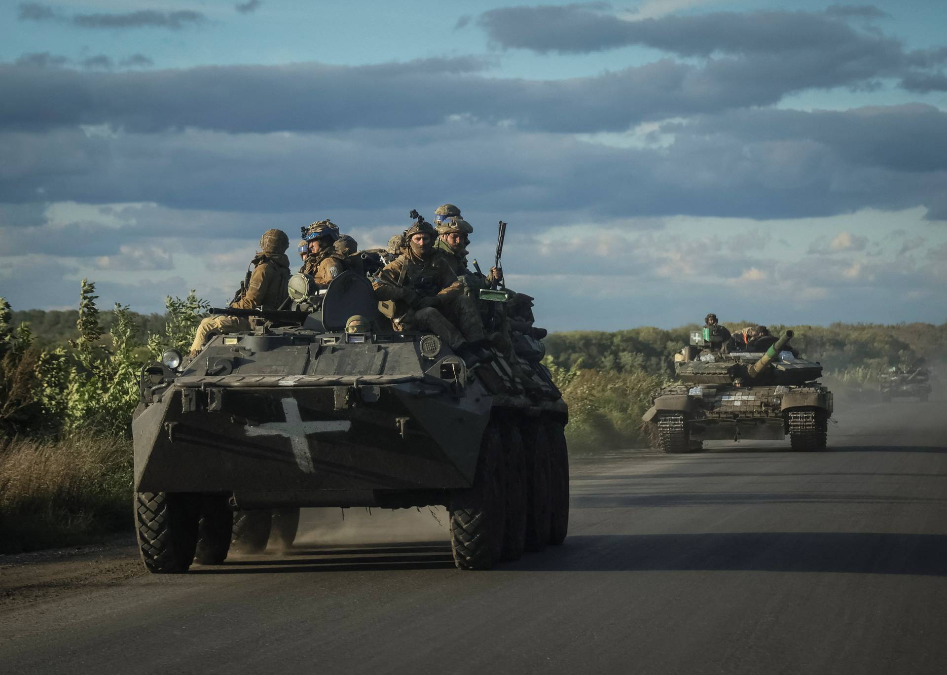 Ukrainian servicemen ride on Armoured Personnel Carrier (APC) and a tank in the town of Izium