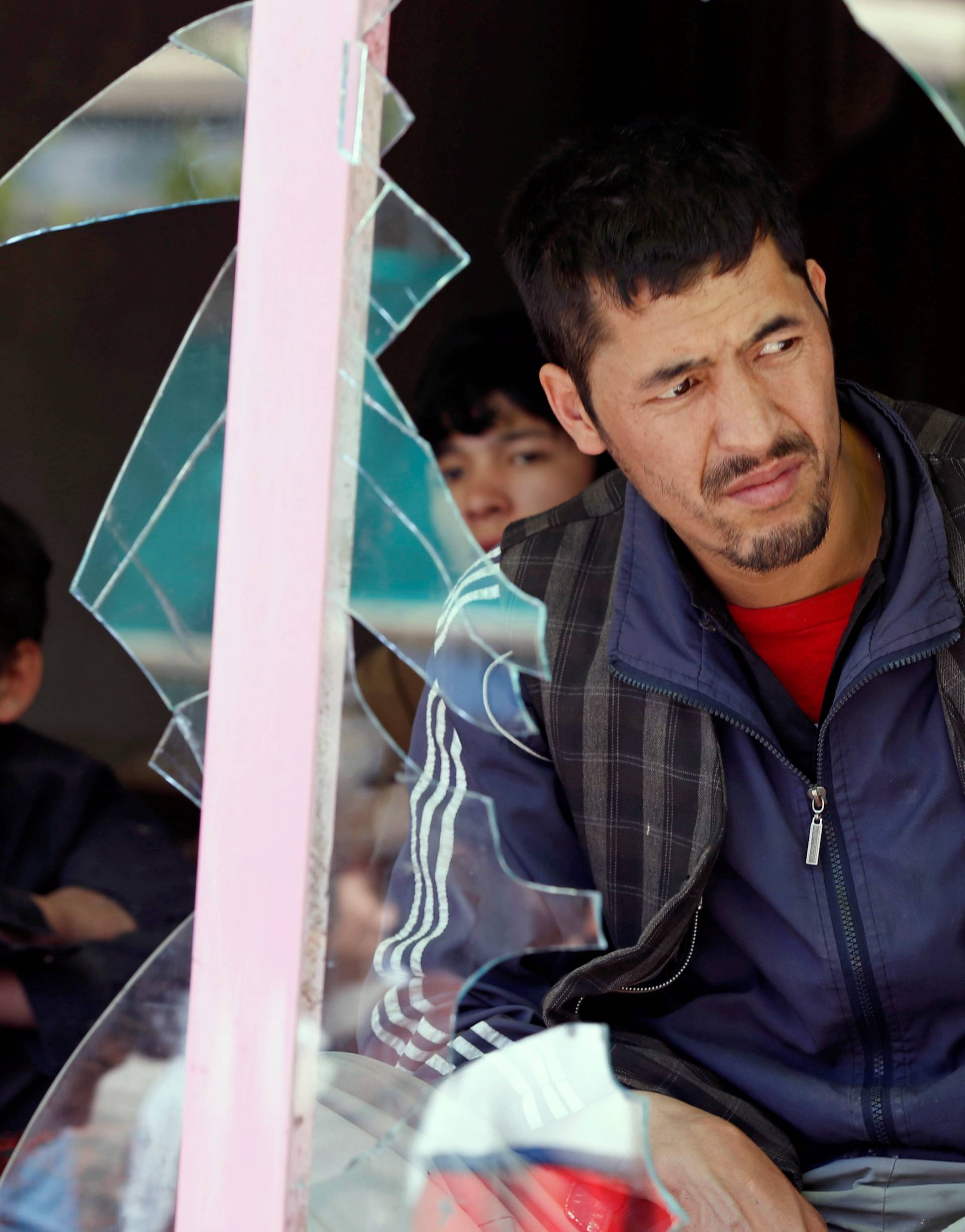 Afghan men look out through a broken window at the site of a suicide attack in Kabul