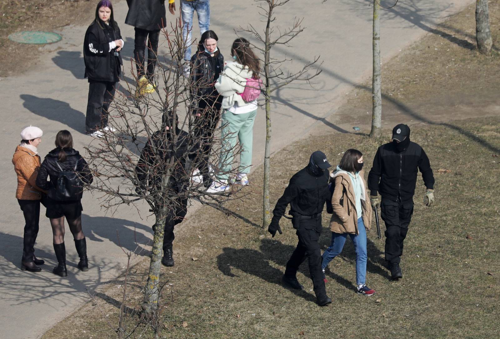 A woman is led away by law enforcement officers, as Belarusian opposition supporters gather for a rally in Minsk