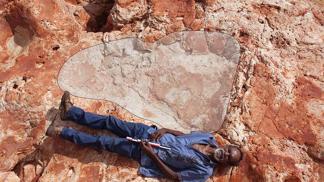 A supplied image of Aboriginal elder and Goolarabooloo Law Boss Richard Hunter alongside a 1.75m sauropod dinosaur track in the Lower Cretaceous Broome Sandstone, Walmadany area, Dampier Peninsula, in Western Australia