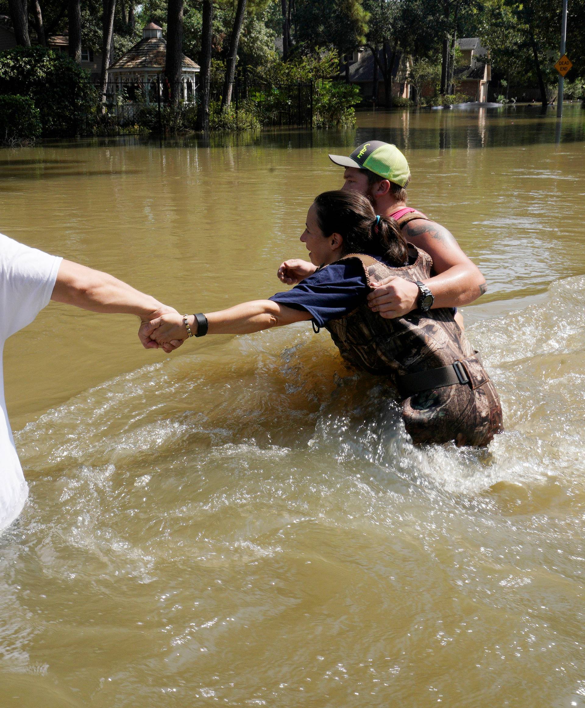 Melissa Ramirez struggles against the current flowing down a flooded street helped by Edward Ramirez and Cody Collinsworth as she tried to return to her home for the first time since Harvey floodwaters arrived in Houston