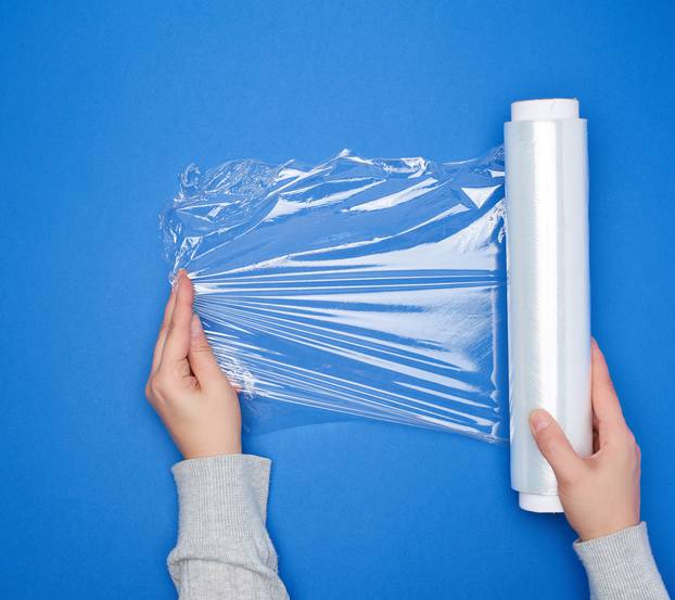 hand hold a large roll of wound white transparent film for wrapp