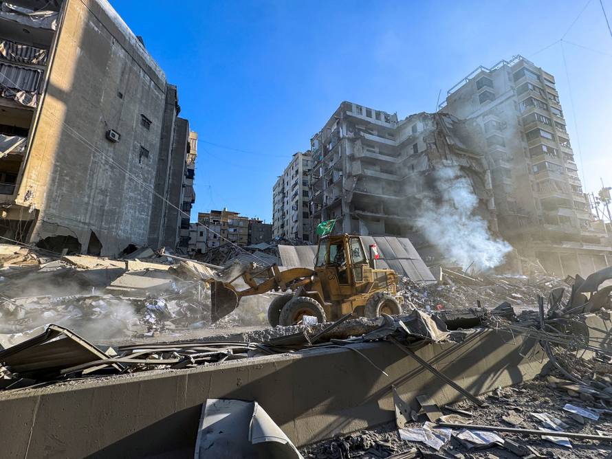 A bulldozer drives along a damaged street amid destruction after an Israeli strike on Beirut's southern suburbs