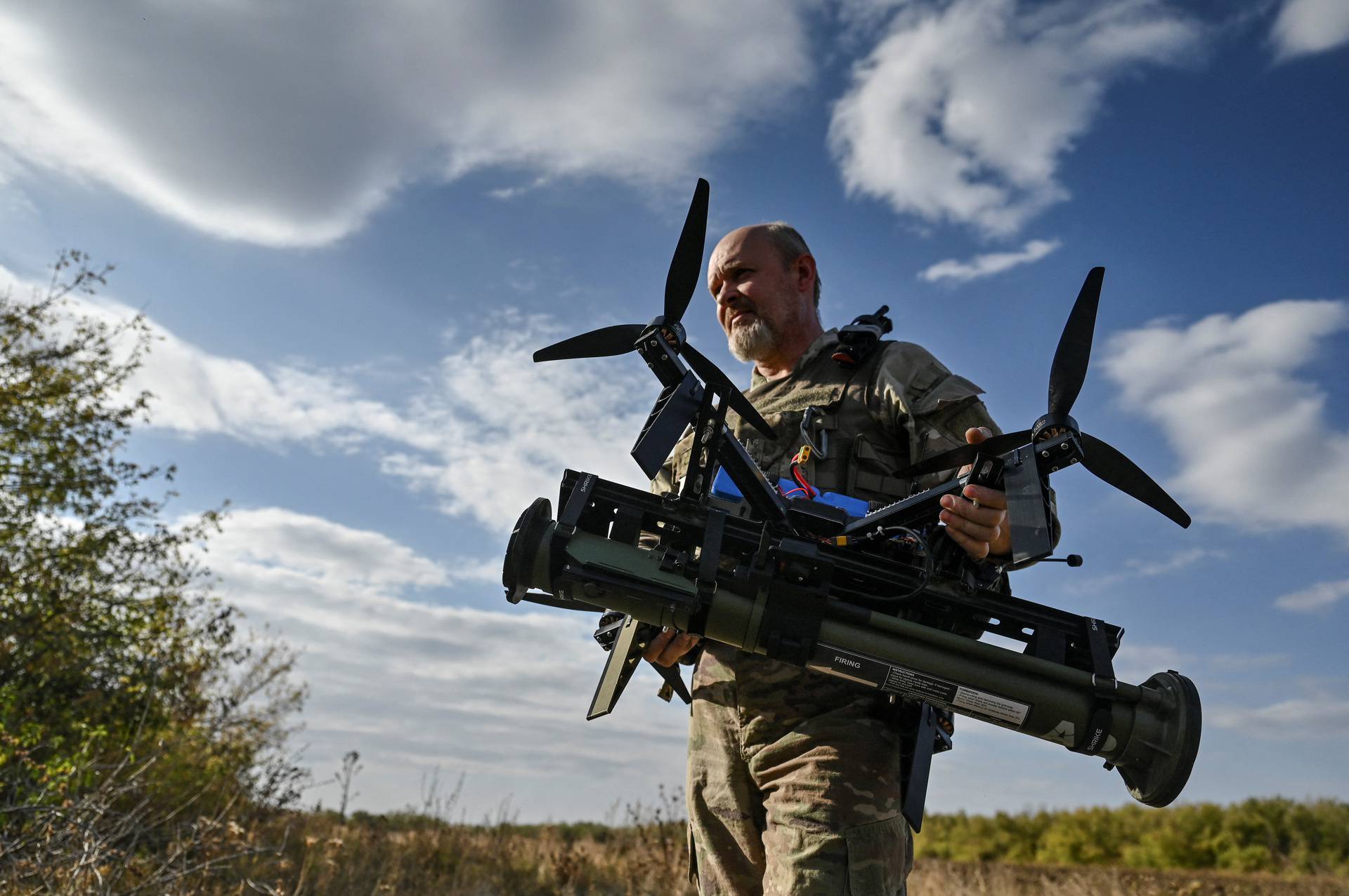 Ukrainian serviceman carries an FPV drone with an attached portable grenade launcher after a test fly at a position near a frontline in the Zaporizhzhia region