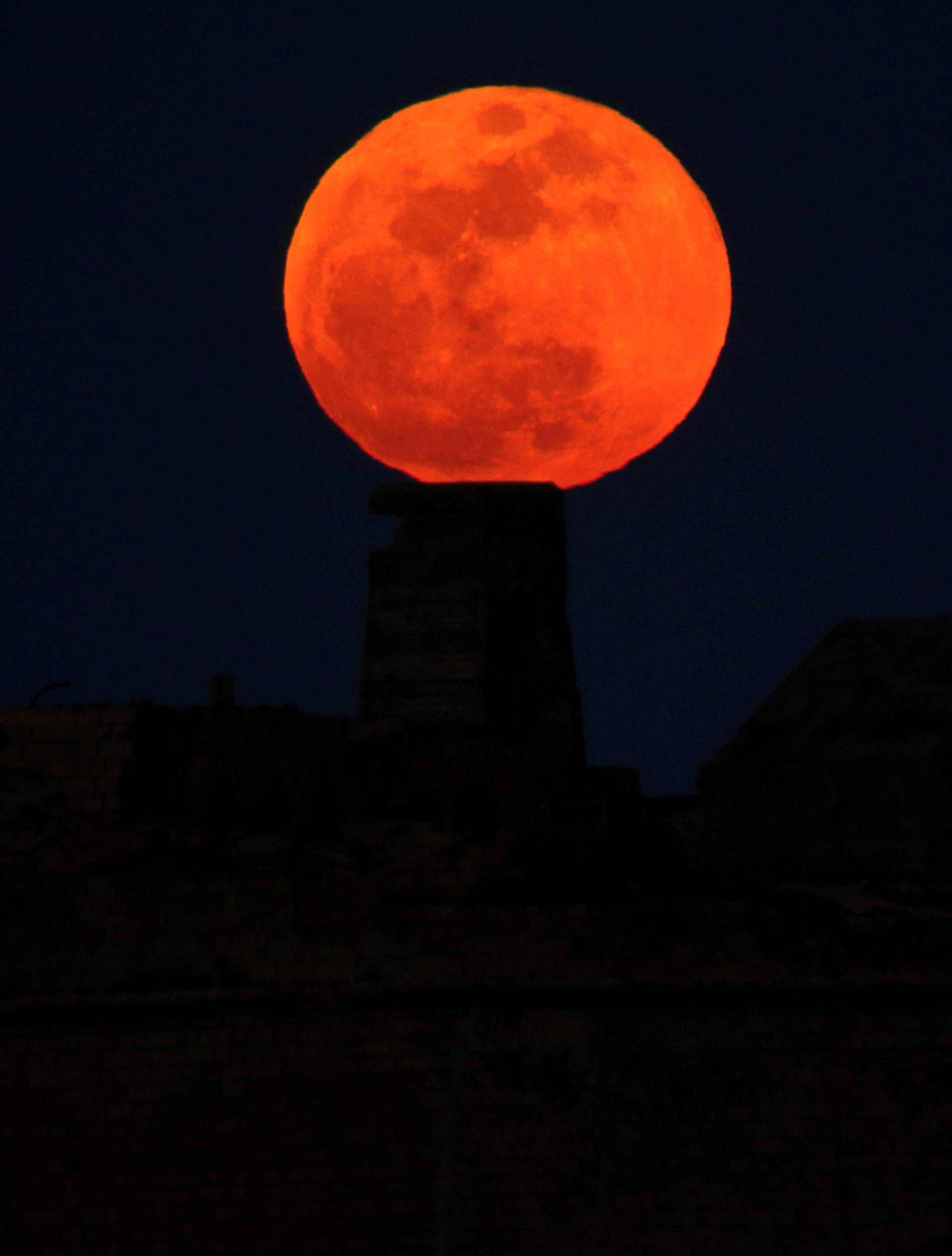 A full moon 'supermoon' rises behind Fort Ricasoli in Valletta's Grand Harbour