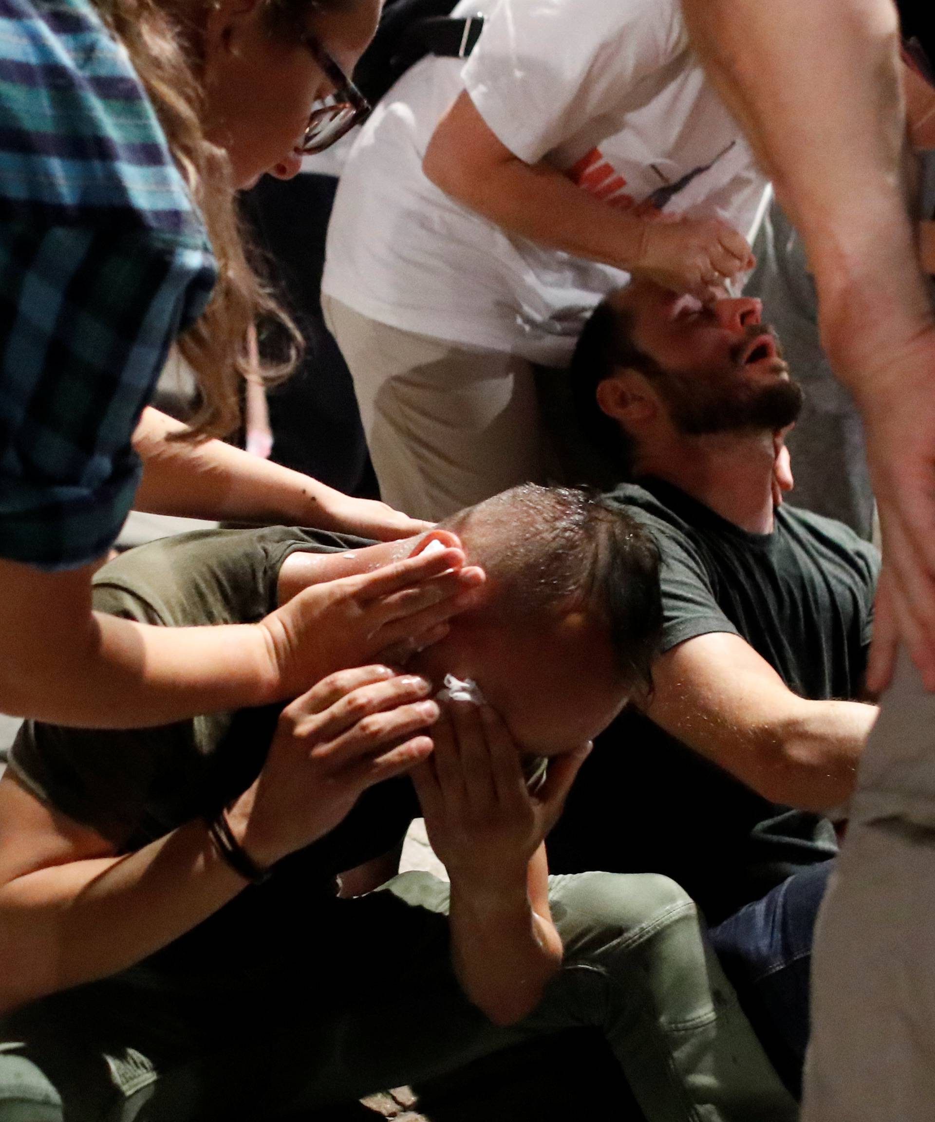 Men are aided after clashes with police officers during the "Chain of lights" protest against judicial overhaul next to Presidential Palace in Warsaw