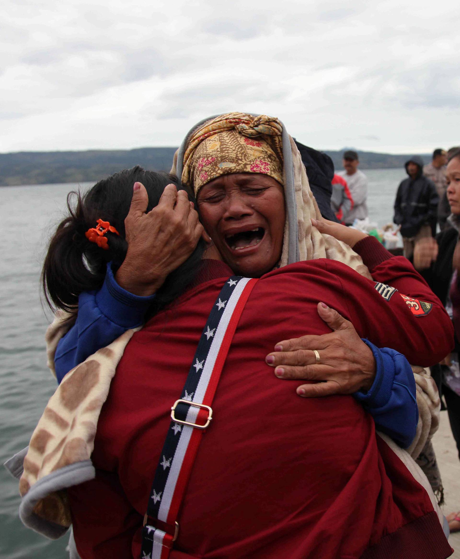 Relatives cry while waiting for news on missing family members who were on a ferry that sank in Lake Toba