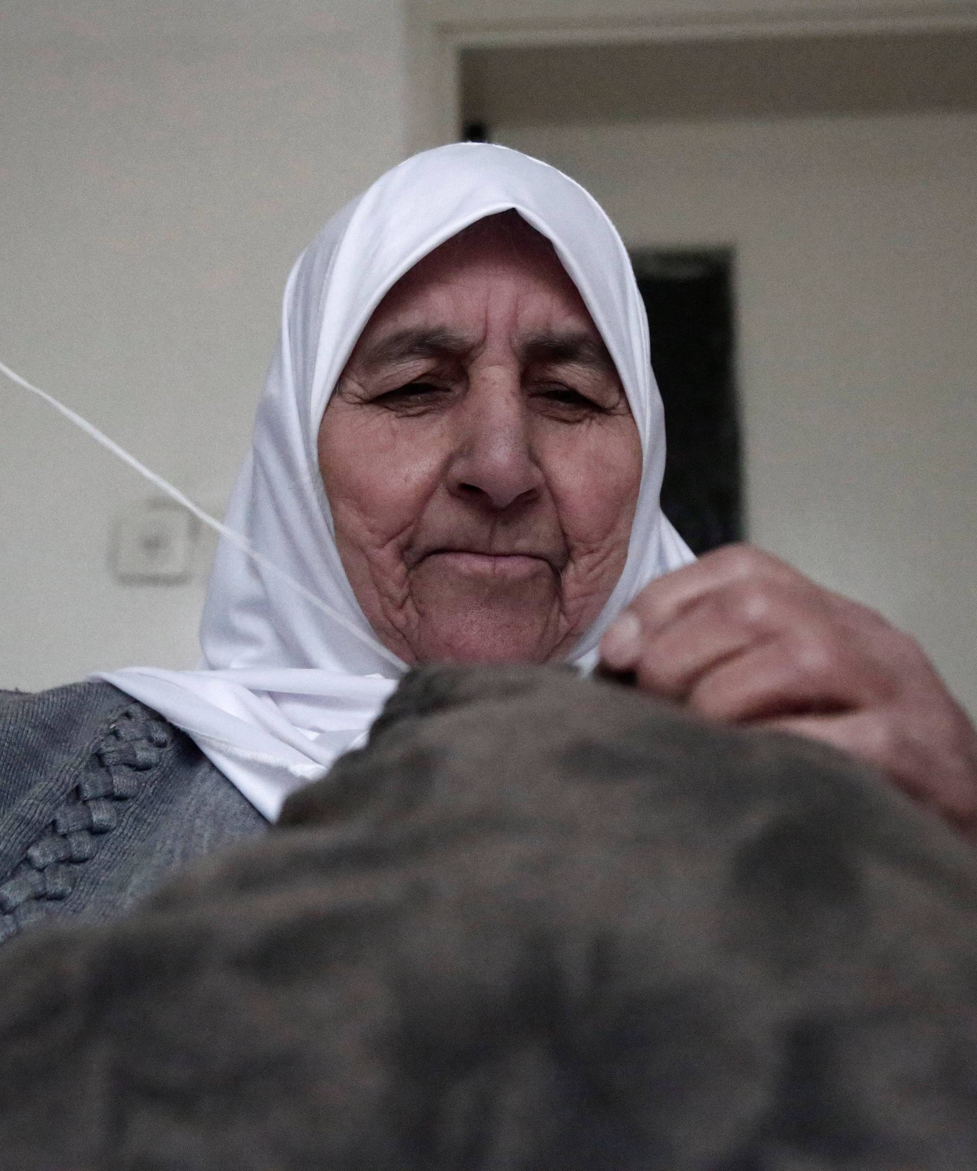 Ezzeya Daraghmeh, an 82-year-old Palestinian woman who said she has kept parts of her hair she cut over 67 years, sews a pillow that she stuffed with her hair, in the West Bank town of Tubas