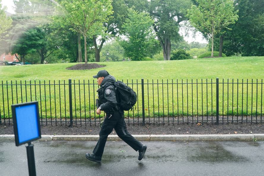 A U.S. Secret Service agent runs after alleged gunshots were heard nearby, at the White House in Washington