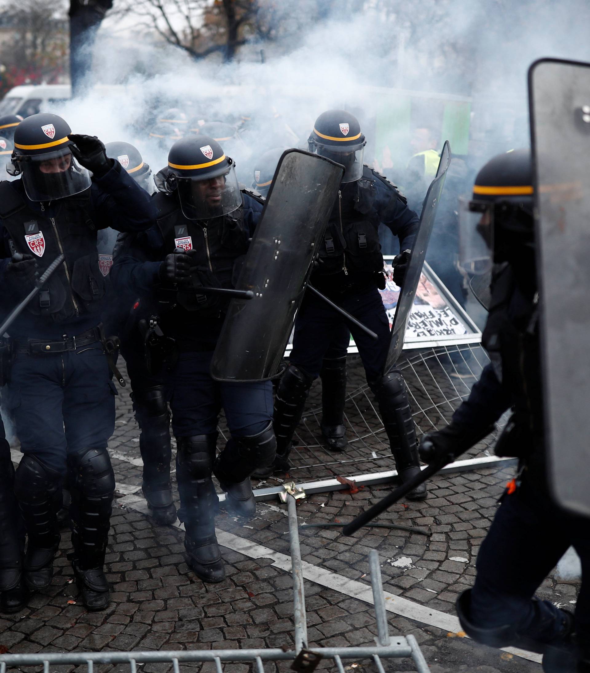 Police officers fire a tear gas during protests against higher fuel prices, on the Champs-Elysee in Paris