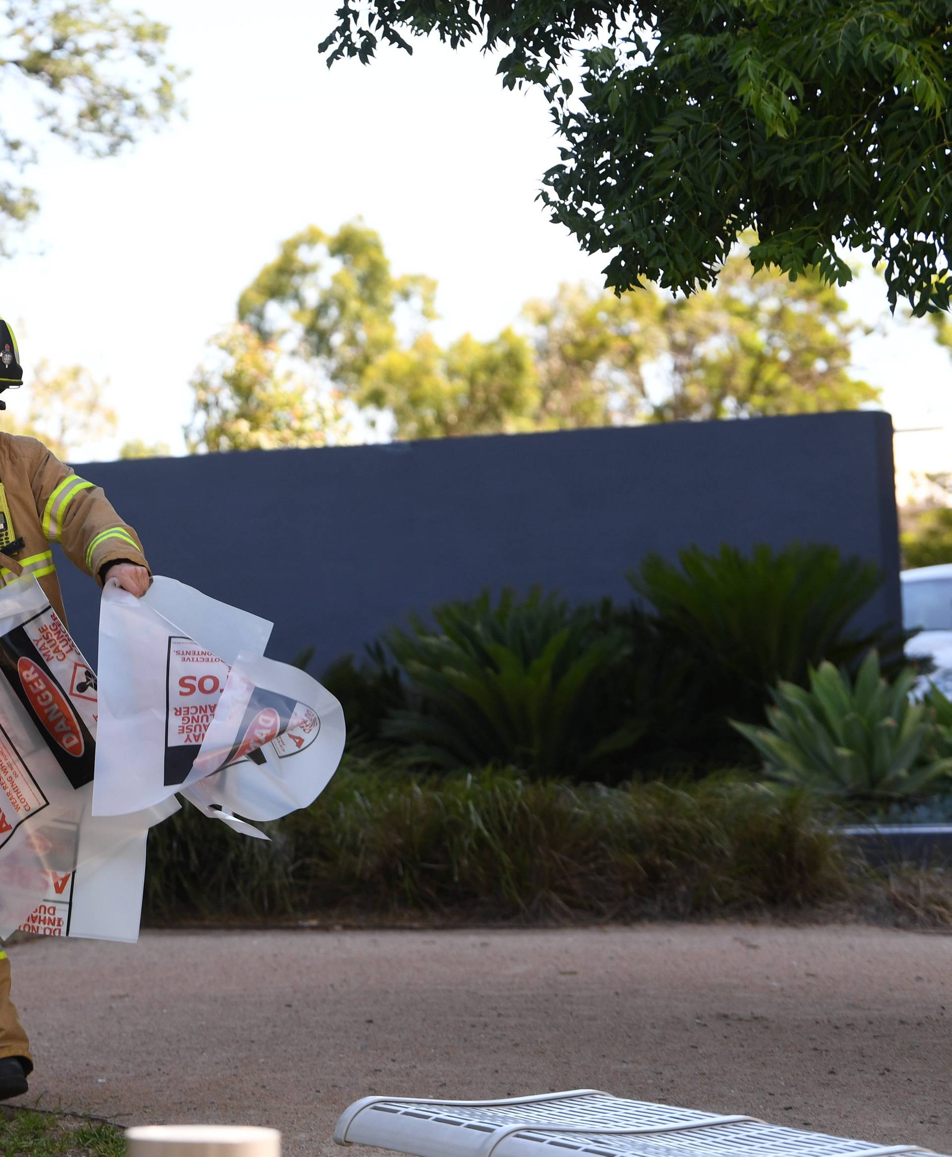 A fire fighter is seen carrying hazardous material bags into the South Korean consulate in Melbourne