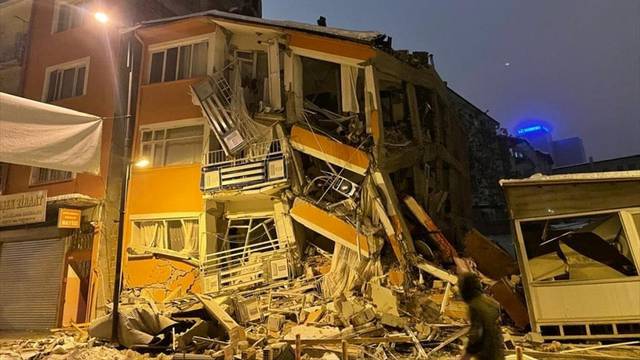 A man walks past by a collapsed building after an earthquake in Malatya