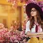 Outdoor portrait of young beautiful fashionable lady posing near flowering tree. Model wearing stylish accessories and clothes. Girl looking aside. Female beauty, fashion concept. City lifestyle. Copy space for text