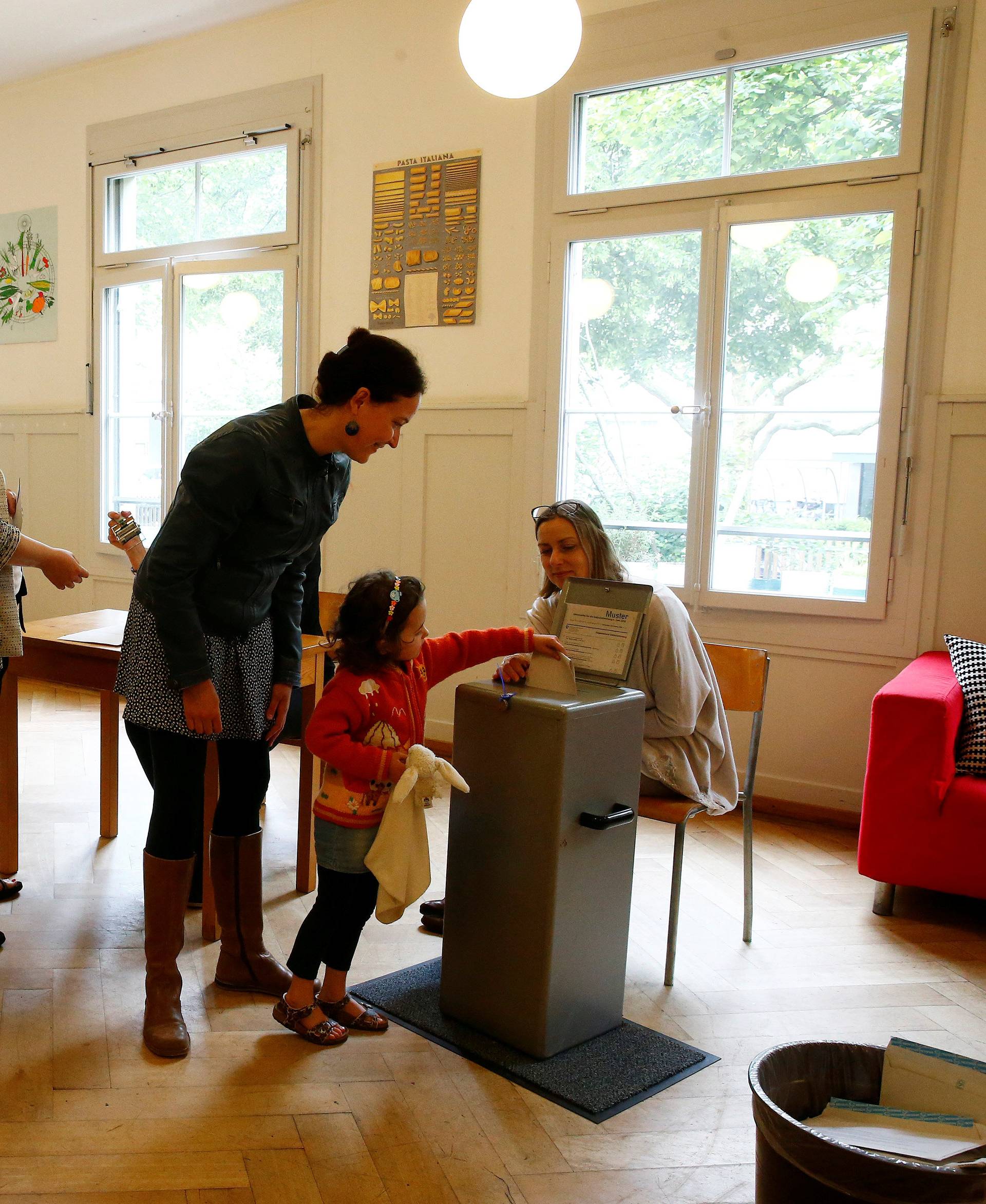 People cast their ballots during a vote on whether to give every adult citizen a basic guaranteed monthly income of 2,500 Swiss francs ($2,560), in a school in Bern