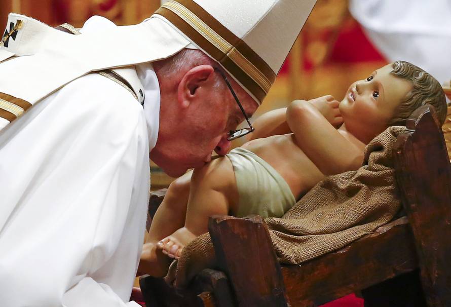 Pope Francis kisses a statue of baby Jesus at the end of the Christmas night Mass in Saint Peter's Basilica at the Vatican