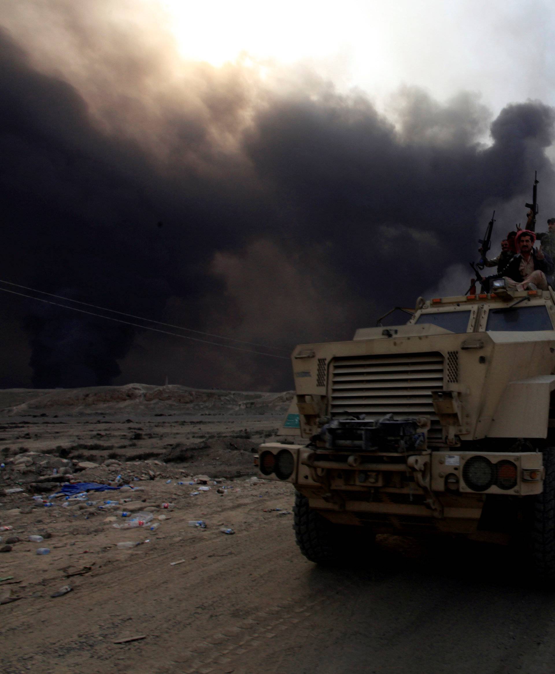 Iraqi army personnel ride on a military vehicle in Qayyarah 