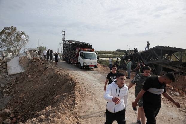 Displaced people cross the bridge linking southern Lebanon to the rest of the country, which was hit earlier in an Israeli strike, in Qasmiyeh