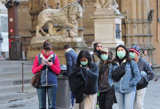 People wearing protective masks walk through Florence as Italy battles a coronavirus outbreak