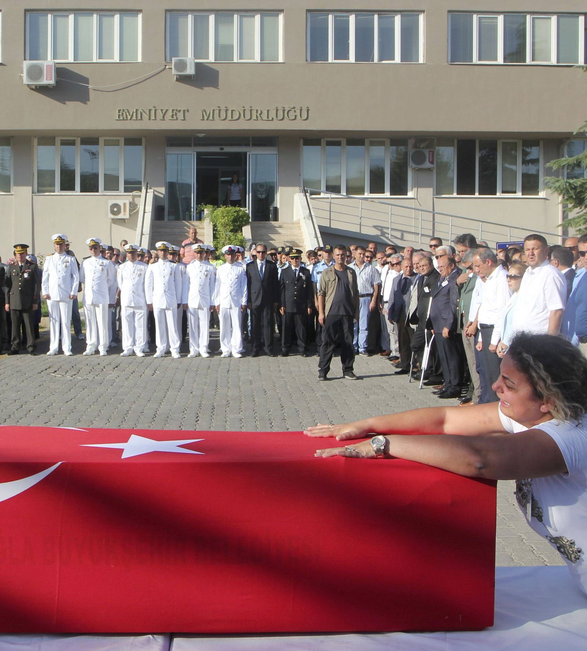 A relative mourns over the coffin holding body of police officer Nedip Cengiz Eker during a funeral ceremony in Marmaris